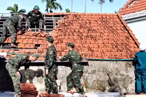 Bộ đội giúp dân lợp lại mái ngói sau bão số 13. 