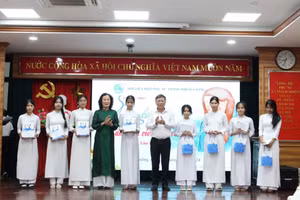 Ông Lê Văn Trung (thứ 5, từ trái qua) - Chủ tịch Ủy ban MTTQ Việt Nam TP Đà Nẵng trao áo dài và quà cho nữ sinh vượt khó. 