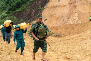 Bộ đội, dân quân tự vệ mang nhu yếu phẩm vượt qua những điểm sạt lở để hỗ trợ Nhân dân.