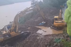 Xe múc đưa giáo viên qua khu vực sạt lở đến đến trường. 