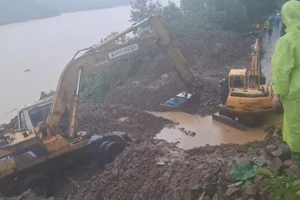 Xe múc đưa giáo viên qua khu vực sạt lở đến đến trường. 