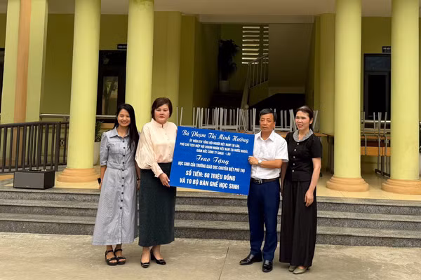 Bà Phạm Thị Minh Hường (thứ 2 từ trái qua) trao tặng tiền và bàn ghế cho nhà trường.