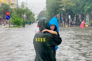 Cán bộ, chiến sĩ hỗ trợ người dân đưa trẻ nhỏ ra khỏi khu vực ngập sâu.