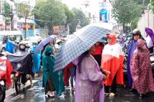 Phụ huynh đội mưa chờ đón thí sinh dự thi môn Ngữ văn vào sáng 26/6.