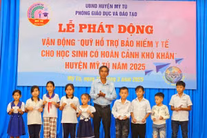Ông Nguyễn Thanh Phong, Phó Chủ tịch UBND huyện Mỹ Tú (Sóc Trăng) trao thẻ bảo hiểm cho các em học sinh. (Ảnh: Xuân Lương)