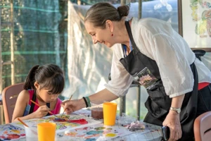 Cô Andrea Teufel hướng dẫn cho học sinh làm quen với kỹ thuật vẽ tranh tường cổ truyền cung đình Huế.