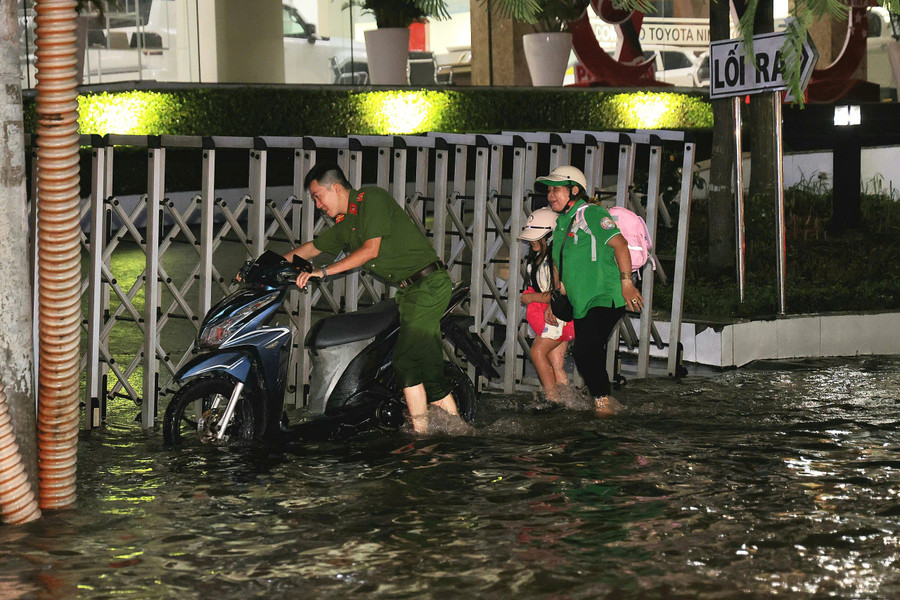 Hình ảnh lực lượng Công an hỗ trợ dắt xe cho người phụ nữ cùng cháu nhỏ gặp khó khăn trên đoạn đường ngập nước. dinh-trieu-lich-su-22.jpg
