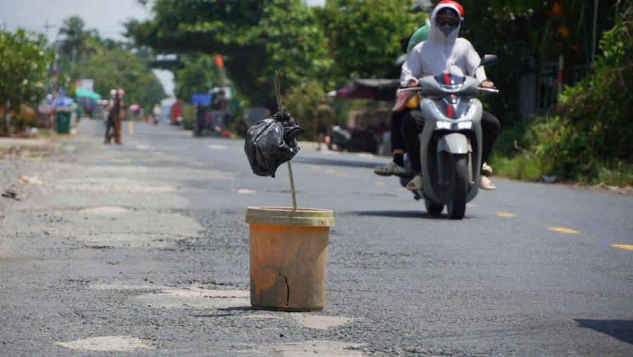 Người dân tự dặm vá đường và đặt những vật dụng cảnh báo tạm thời. (Ảnh: Yến Phương)