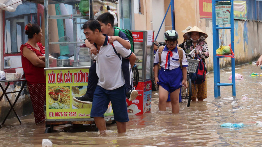 Học sinh và phụ huynh vất vả di chuyển khi triều cường dâng cao.