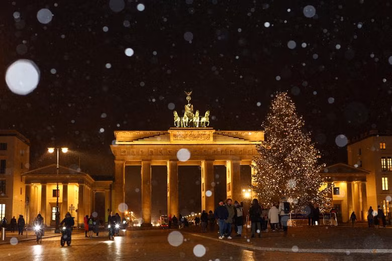 Hình ảnh cây thông Noel được chiếu sáng trước cổng thành Brandenburg khi tuyết rơi ở Berlin, Đức. Ảnh: Reuters/Lisi Niesner.