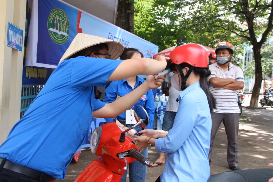 Tình nguyện viên đo thân nhiệt, sát khuẩn cho thí sinh trước khi vào phòng thi.