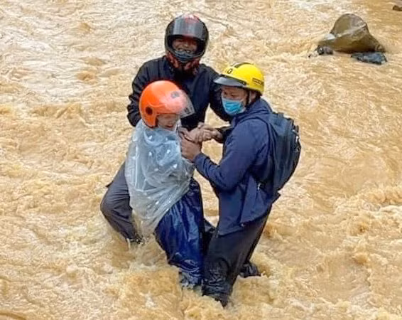Cô giáo được các thầy hỗ trợ qua suối.