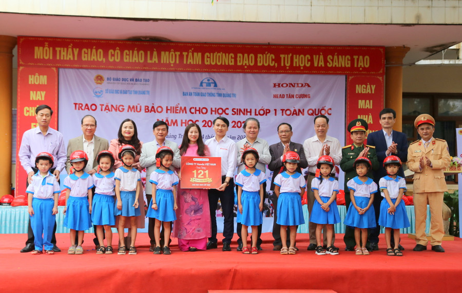 TS Lê Thị Hương, Giám đốc Sở GD&ĐT tỉnh Quảng Trị (thứ 3 bên trái), đại diện Ban An toàn giao thông tỉnh Quảng Trị... tặng mũ bảo hiểm cho học sinh.