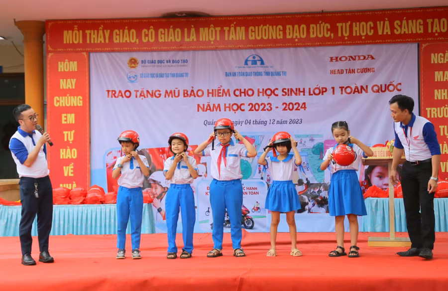 Học sinh được hướng dẫn đội mũ bảo hiểm đúng cách.