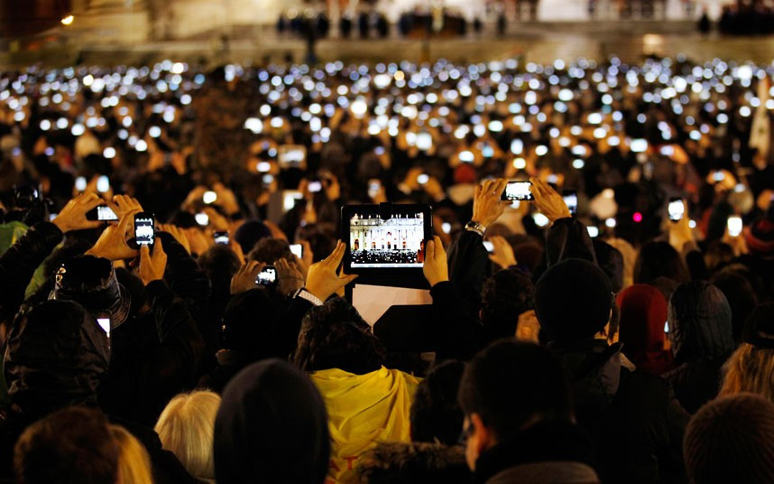 People use smartphones and tablets to take photos of Pope Francis I as he speaks from the central balcony of St Peter’s Basilica at the Vatican