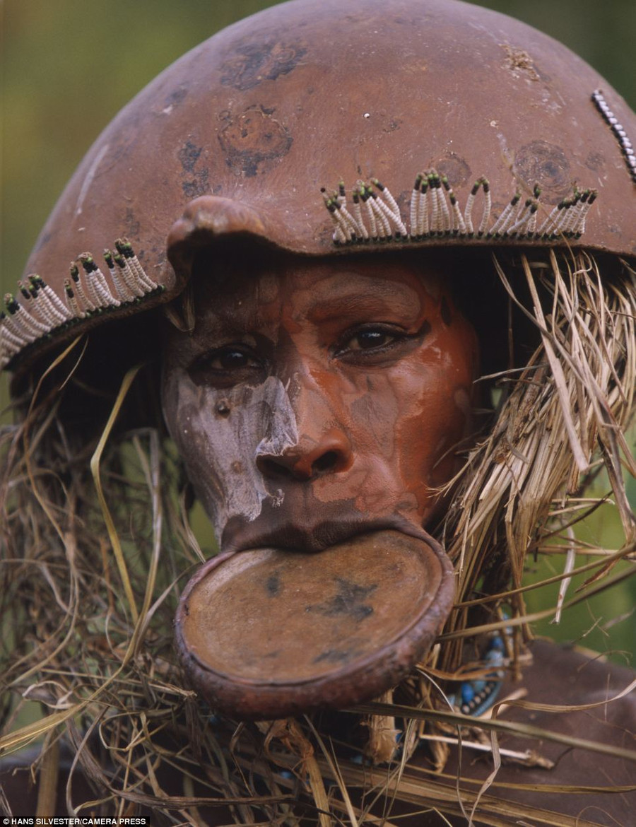 Tribal: This man wears a traditional mouth plate with his straw-covered beaded headdress Read more: http://www.dailymail.co.uk/news/article-2294456/Painted-faces-scarred-bodies-wooden-guns-extravagant-headdresses-Amazing-photographs-reveal-lost-world-Omo-tribes-Ethiopia.html#ixzz2Nn11Sbhn Follow us: @MailOnline on Twitter | DailyMail on Facebook