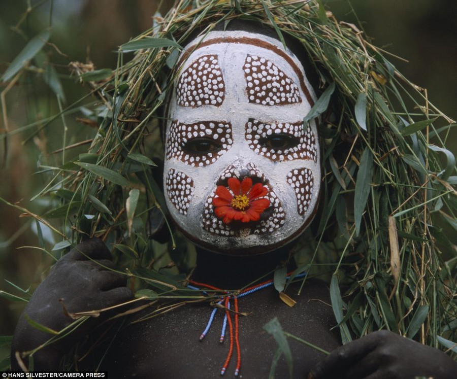 Intricate: This young child is shown with intricate face paint, a bright red flower in his mouth and strings of hand-strung beads Read more: http://www.dailymail.co.uk/news/article-2294456/Painted-faces-scarred-bodies-wooden-guns-extravagant-headdresses-Amazing-photographs-reveal-lost-world-Omo-tribes-Ethiopia.html#ixzz2NmzqpgDO Follow us: @MailOnline on Twitter | DailyMail on Facebook