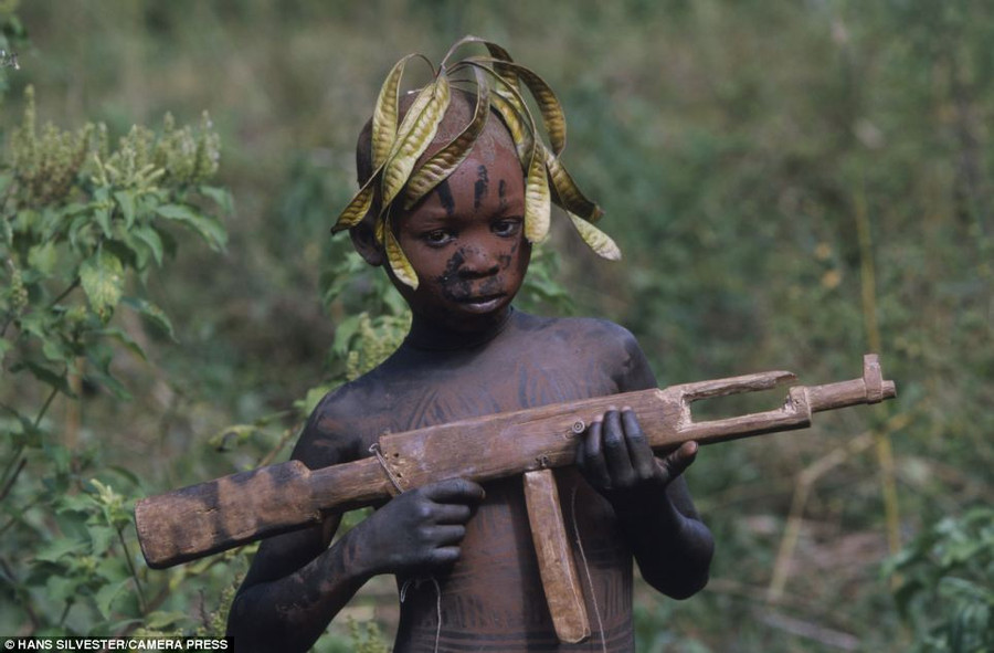 Sharp shooter: A young boy plays with a wooden gun. Although the tribes’ rustic lifestyles are far removed from modern towns and cities influences have crept in Read more: http://www.dailymail.co.uk/news/article-2294456/Painted-faces-scarred-bodies-wooden-guns-extravagant-headdresses-Amazing-photographs-reveal-lost-world-Omo-tribes-Ethiopia.html#ixzz2Nn74RpeC Follow us: @MailOnline on Twitter | DailyMail on Facebook