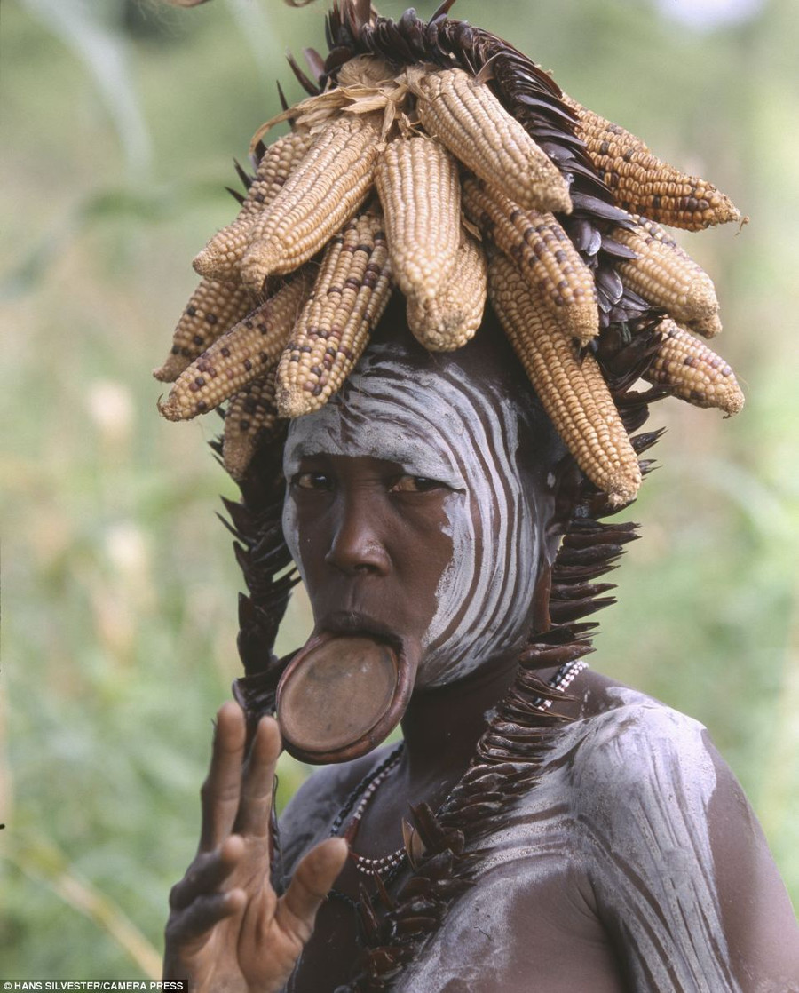 Traditional: A woman with her face painted in white circles wears a crown of dried corn and a mouth plate Read more: http://www.dailymail.co.uk/news/article-2294456/Painted-faces-scarred-bodies-wooden-guns-extravagant-headdresses-Amazing-photographs-reveal-lost-world-Omo-tribes-Ethiopia.html#ixzz2Nn0S8Alo Follow us: @MailOnline on Twitter | DailyMail on Facebook