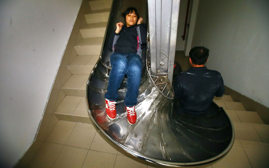 An emergency slide is tried out in a building in Shanghai, China. The stainless steel chute has been attached to the banister of the stairs. The idea is that in an emergency the slide would be deployed and people would use it to exit the building quickly rather than using the stairs. According to inventor Zhou Miaorong people using the slide could escape from a five-storey building in 14 seconds.