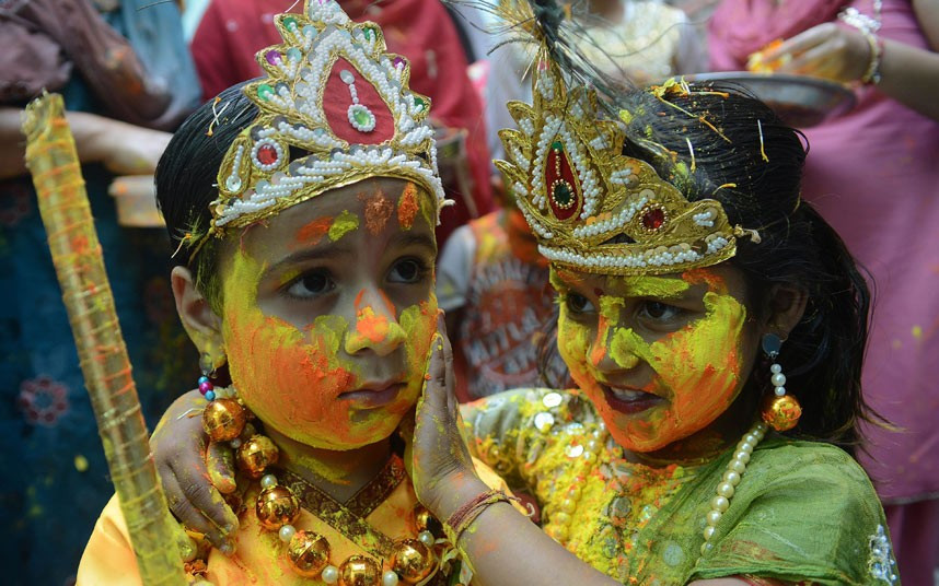 Indian children dressed as Lord Krishna (L) and Radha play with coloured powder during a Holi celebration at a temple in Amritsar