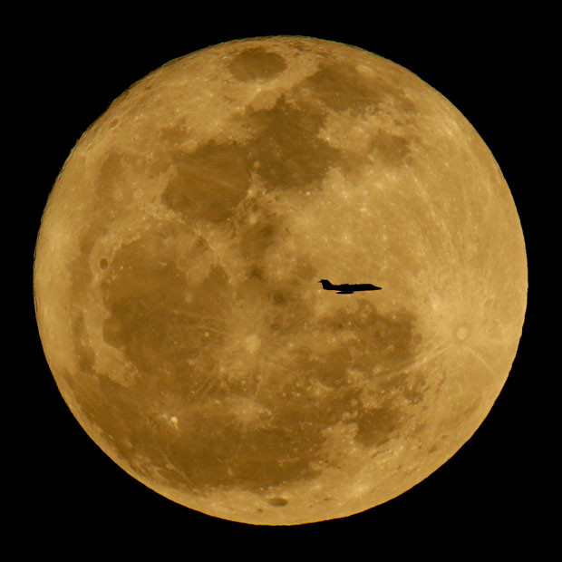 Những hình ảnh ấn tượng trong tuần ảnh 7 A small jet is silhouetted against the rising full moon in the skies above Phoenix, Arizona
