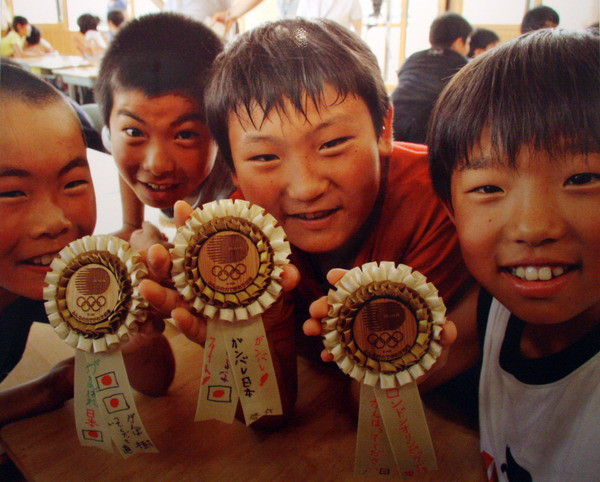 Bùa may mắn – Học sinh trường tiểu học Iriya thuộc thị trấn Minami – sanriku, quận Miyagi, làm bùa may mắn dành tặng các thành viên đội tuyển Olympic Nhật Bản tham dự Thế Vận Hội Luân Đôn 2012. Bùa may mắn được làm từ các mảnh vụn gạch đá sau thảm họa.
