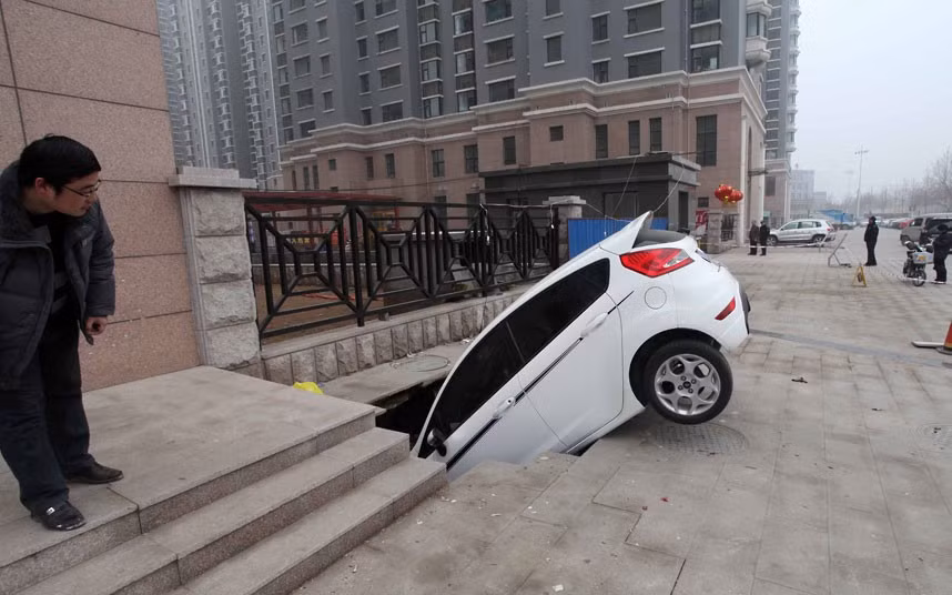 A car is trapped in a huge hole after a cave-in happened at a gate of a residential community in Weifang, China