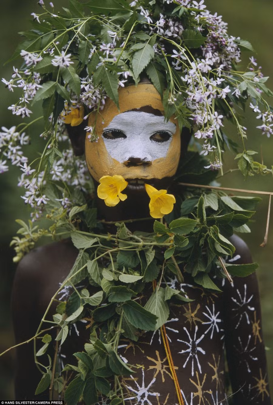 A flower in your hair: This youngster sports a floral headdress and a brightly painted face and body Read more: http://www.dailymail.co.uk/news/article-2294456/Painted-faces-scarred-bodies-wooden-guns-extravagant-headdresses-Amazing-photographs-reveal-lost-world-Omo-tribes-Ethiopia.html#ixzz2Nn0IyK53 Follow us: @MailOnline on Twitter | DailyMail on Facebook