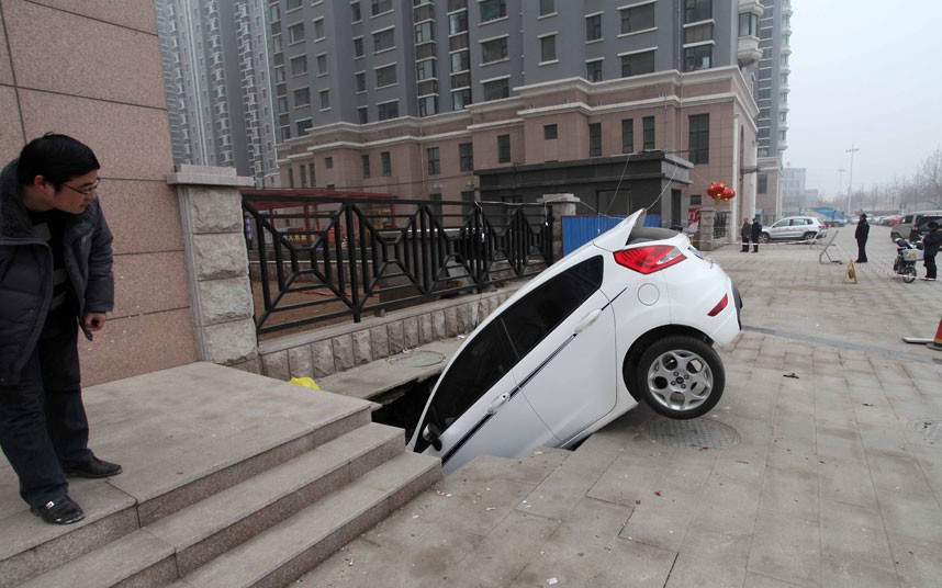 Những hình ảnh ấn tượng trong tuần ảnh 3 A car is trapped in a huge hole after a cave-in happened at a gate of a residential community in Weifang, China