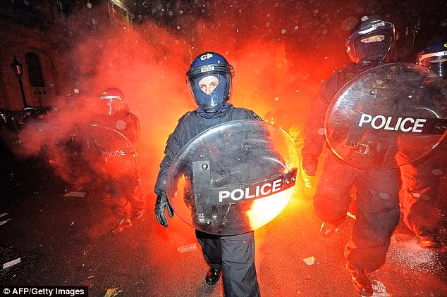Riot police come under attack from flares as they clashed with protesters Read more: http://www.dailymail.co.uk/news/article-1337088/TUITION-FEES-VOTE-PROTEST-Charles-Camillas-car-attacked-thousands-students-descend-Parliament.html#ixzz17fylTKXn