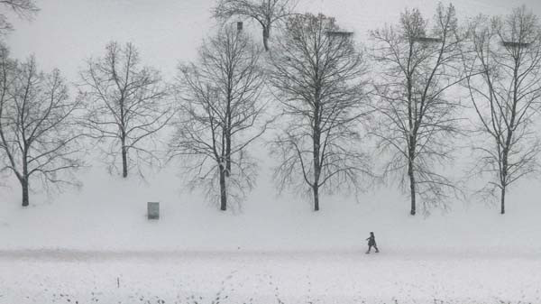 A person walks along a snow covered street in Berlin, December 17, 2010