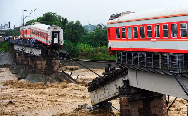 A passenger train is seen on a partially destroyed railway bridge after two of its carriages fell into the river in Xiaohan town of Guanghan, Sichuan province