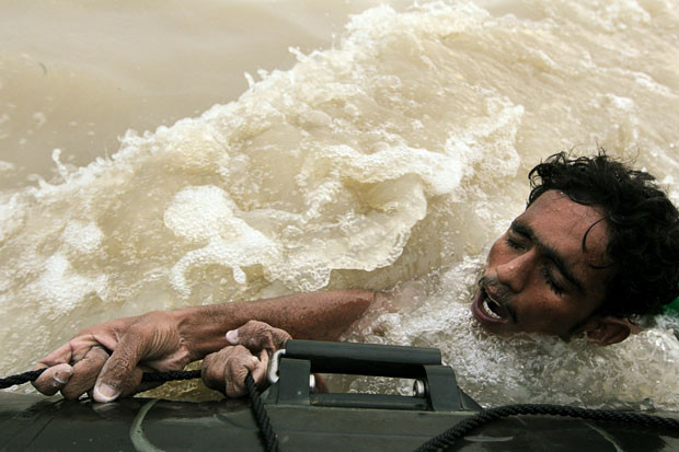 Những thảm họa thiên nhiên, một năm nhìn lại ảnh 16 Flood victim Mohammed Nawaz hangs onto a moving raft as he is rescued by the Pakistan Navy in Sukkur