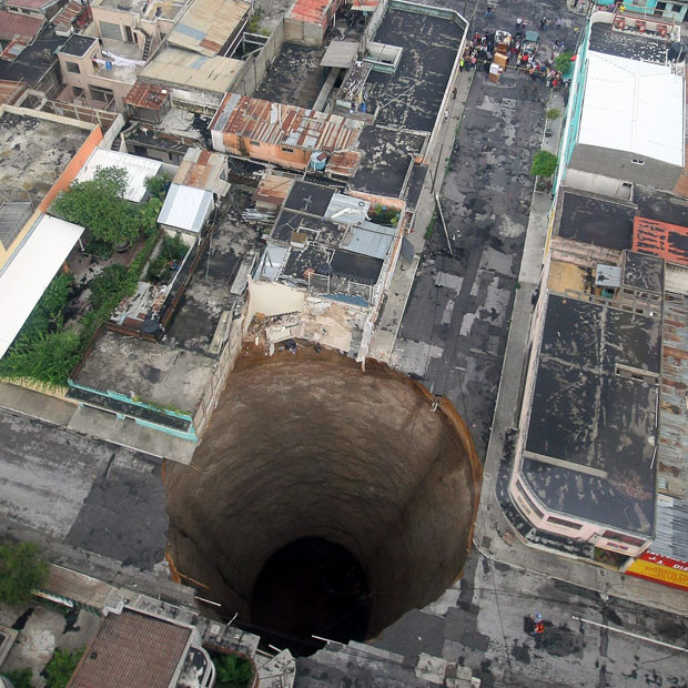 Những thảm họa thiên nhiên, một năm nhìn lại ảnh 14 A cavernous and almost perfectly round sinkhole swallowed an entire intersection in Guatemala City during a tropical storm. The hole is 66 feet across and plunges nearly 100 feet down. Geologists said that the circular shape suggested a cave formation underneath, but what exactly caused the sinkhole was still a mystery