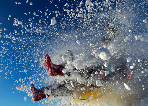 A sledger’s boots are visible in an explosion of snow during an attempt to jump a ramp at the Queen Elizabeth country park near Petersfield in Hampshire