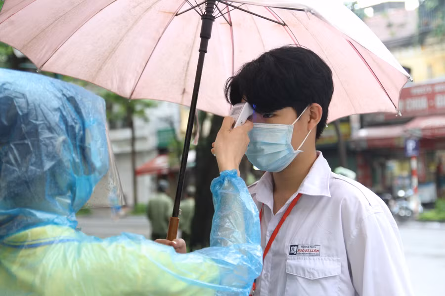 Các thí sinh tham dự kỳ thi tuyển sinh lớp 10 tại điểm thi trường THPT Việt Đức được đo thân nhiệt trước khi vào điểm thi.