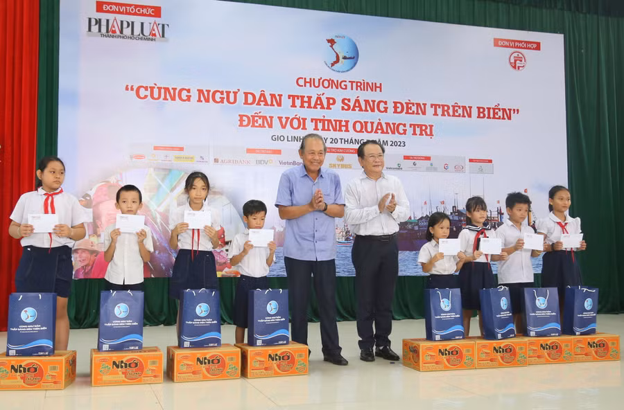 Nguyên Phó Thủ tướng Thường trực Chính phủ Trương Hòa Bình và lãnh đạo báo Pháp Luật TP.HCM trao học bổng động viên học sinh.