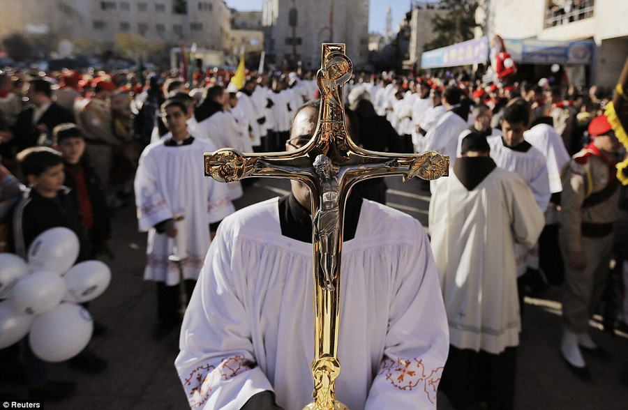 A priest holds a cross as he awaits the arrival of the Latin Patriarch of Jerusalem, Fouad Twal, outside the Church of Nativity Read more: http://www.dailymail.co.uk/news/article-2528947/Crowds-gather-Bethlehem-Christmas-Eve-celebrations-amid-calls-peace-Middle-East.html#ixzz2oS2FcxuF Follow us: @MailOnline on Twitter | DailyMail on Facebook