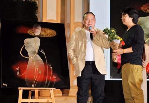 Họa sĩ Đinh Quân (phải) trao hoa cho vị mạnh thường quân mua bức Trinh nữ của anh với giá 210 triệu đồng.