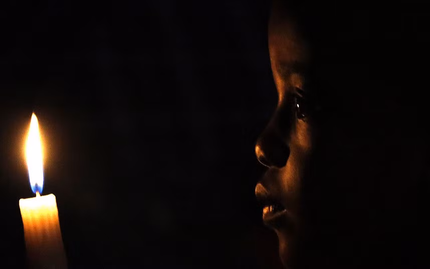 A South African boy holds a candle during a homage outside the Houghton home of the late former South African President Nelson Mandela in Johannesburg