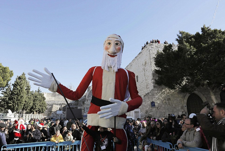 Celebrations: A performer entertains children with a giant Santa Claus puppet at a Christmas parade in Manger Square Read more: http://www.dailymail.co.uk/news/article-2528947/Crowds-gather-Bethlehem-Christmas-Eve-celebrations-amid-calls-peace-Middle-East.html#ixzz2oS22iTgV Follow us: @MailOnline on Twitter | DailyMail on Facebook