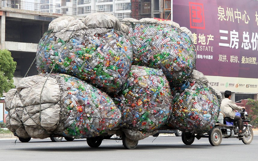 Những hình ảnh ấn tượng trong tuần ảnh 1 A man drives a motorised tricycle carrying bags of plastic bottles for recycling in Jinjiang, China