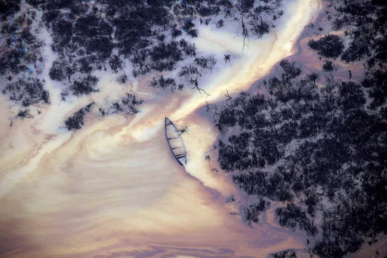 Oil floats on the surface near an illegal oil refinery in Ogoniland, outside Port Harcourt, in Nigeria’s Delta region on March 24, 2011