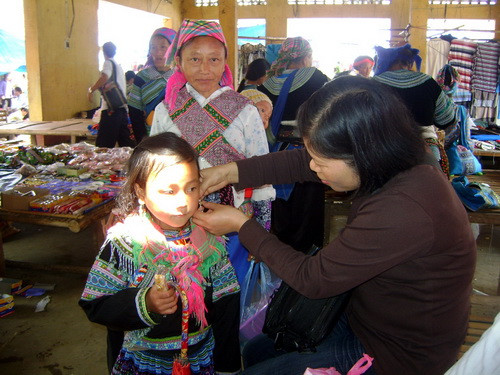 Gặp ở chợ phiên, cô giáo người Kinh tặng hoa tai làm đẹp cho em bé người Mông