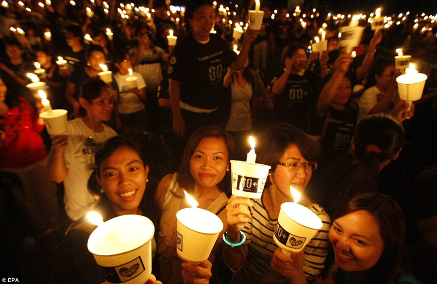 Filipinos light candles in Makati city, south of Manila, Philippines to shine a light on climate change Read more: http://www.dailymail.co.uk/news/article-2123195/Earth-Hour-2012-Iconic-buildings-world-turn-lights-highlight-climate-change.html#ixzz1qkjmraEp
