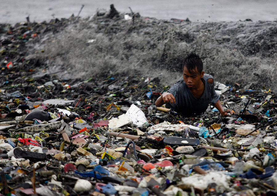 A boy is hit by waves as he collects recyclable materials from garbage washed onto the shore along Manila Bay in Manila on August 27, 2011. (Cheryl Ravelo/Reuters)