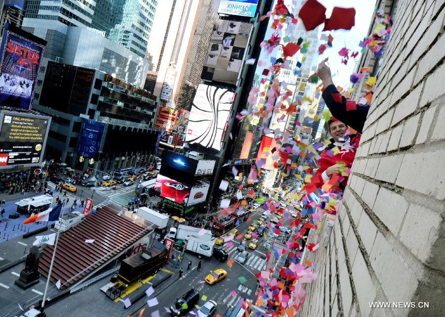 Staff members toss confetti from a window during the annual 
