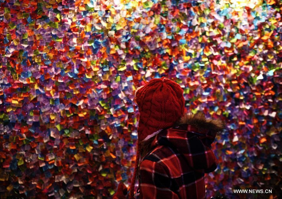 　A girl looks at the confetti on the New Year’s Eve Wishing Wall at Times Square Information Center in New York, the United States, Dec. 29, 2011. All the pieces of confetti, bearing the best wishes for the year 2012 from people around the world, will rain down to revelers during the New Year’s Eve celebration on Times Square
