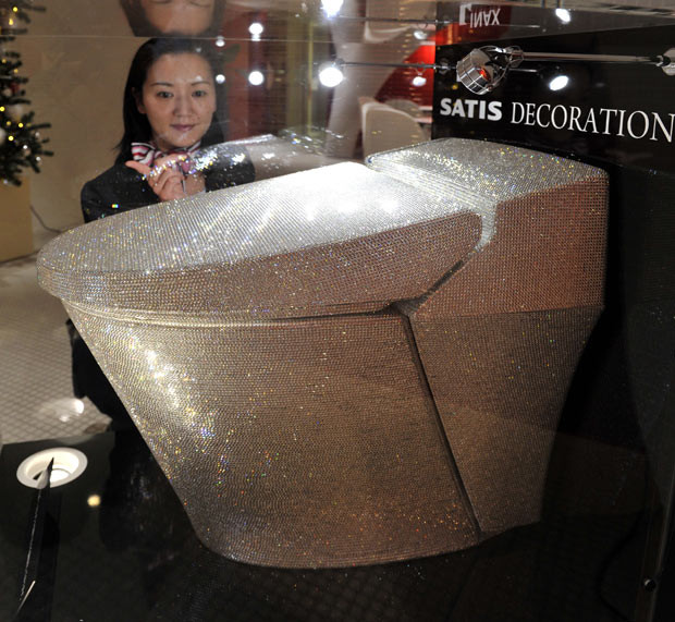 An employee of Lixil, a tiling and sanitary fixtures manufacturer, displays a toilet decorated with 72,000 Swarovski crystals at a showroom in Tokyo